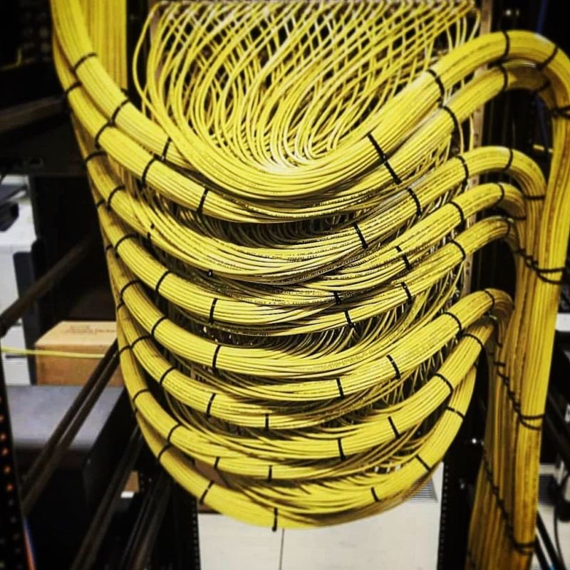 Yellow network cables neatly bundled and routed with black zip ties for organized server rack cable management.