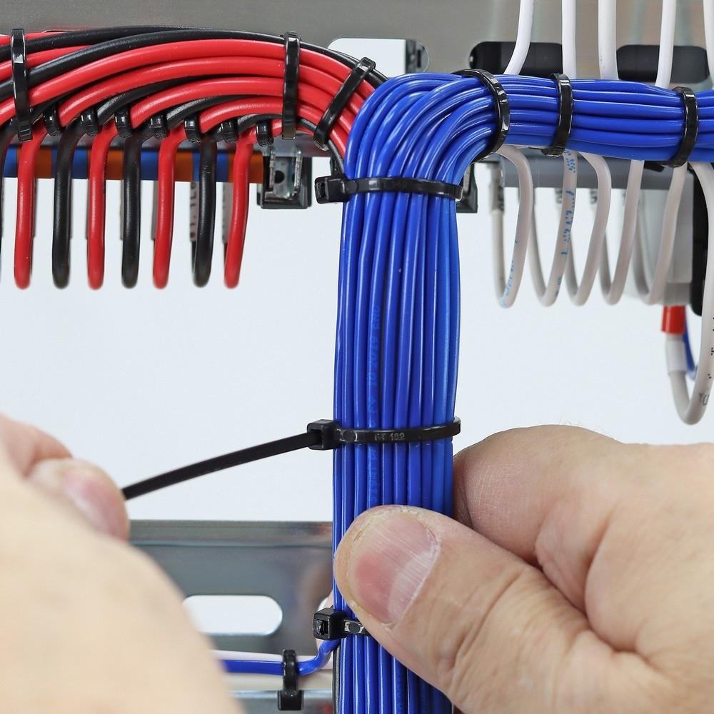 Black heavy-duty zip ties used for secure cable management, organizing red, blue, and white electrical wires in an industrial wiring setup for clean and safe bundling.