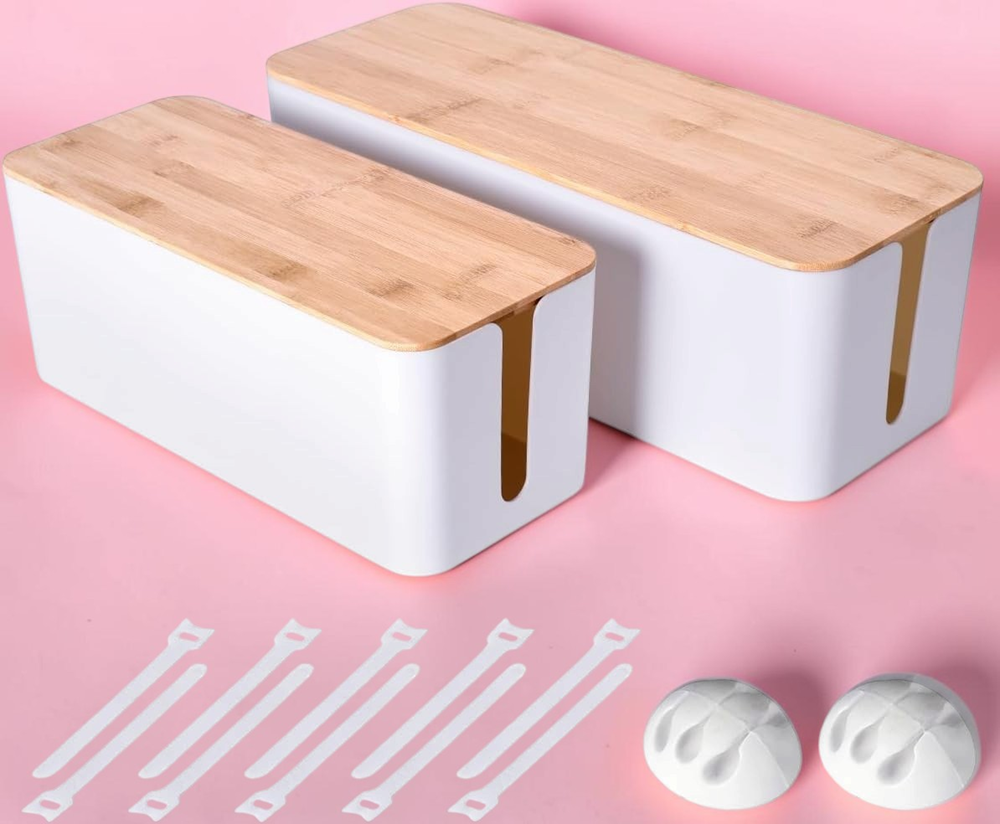 Two white cable management boxes with bamboo lids, five reusable cable ties, and two cable clips on a pink background.